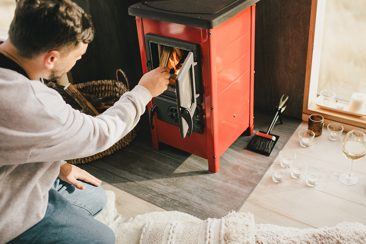 Man adding fuel to a log burner